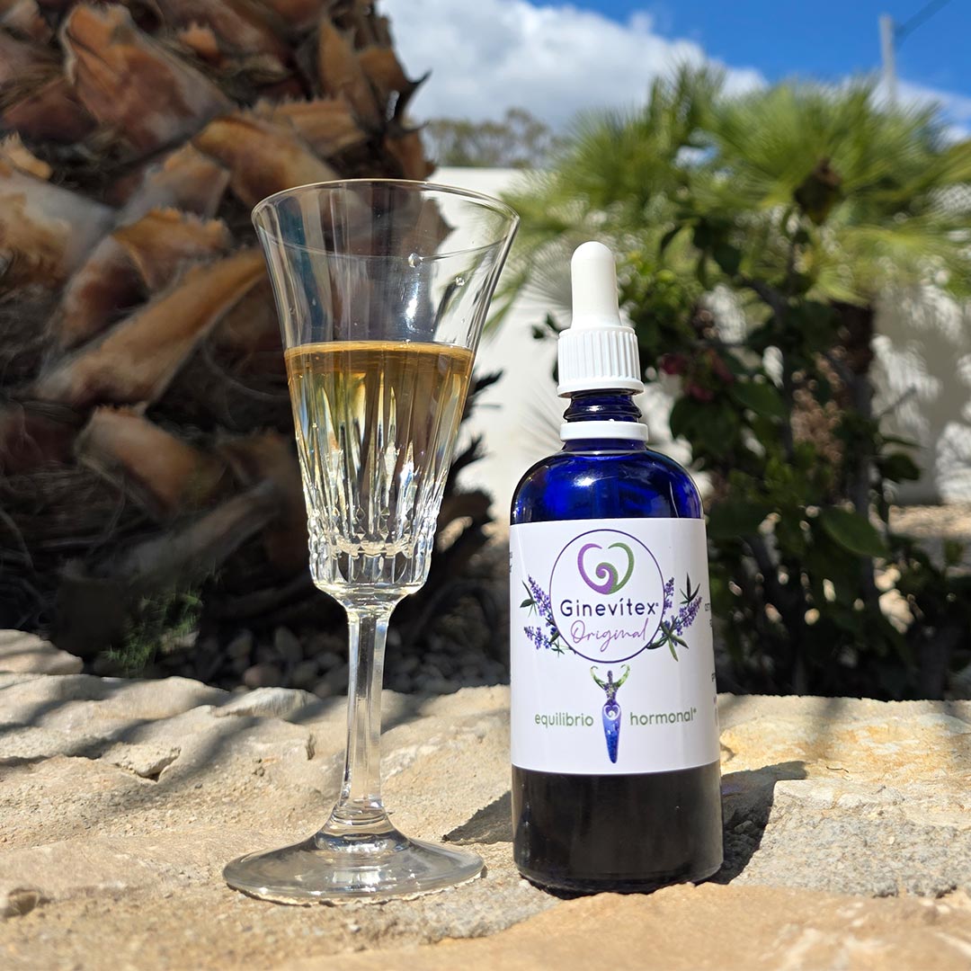 A 100ml bottle of Ginevitex standing net to a glass with water with Ginevitex tincture in it - Elliotti