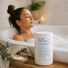 Woman relaxing in a bathtub with Epsom salt and a candle, featuring a product container labeled 'Le sel d'Epsom'.