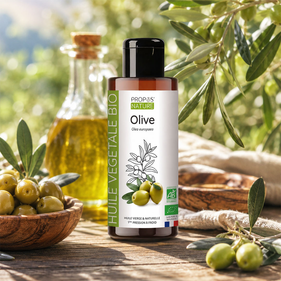A bottle of Propos Nature Bio Olive Vegetable Oil stands on a rustic wooden table surrounded by fresh olives, a wooden bowl, and a glass bottle of oil in the background, with olive branches and leaves framing the scene.