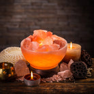 Himalayan salt lamp with candles and crystals on a wooden surface