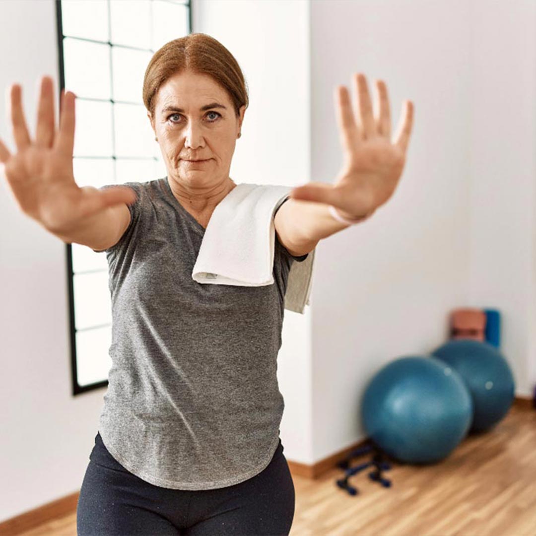 A woman in standing in a gym holding her hands up
